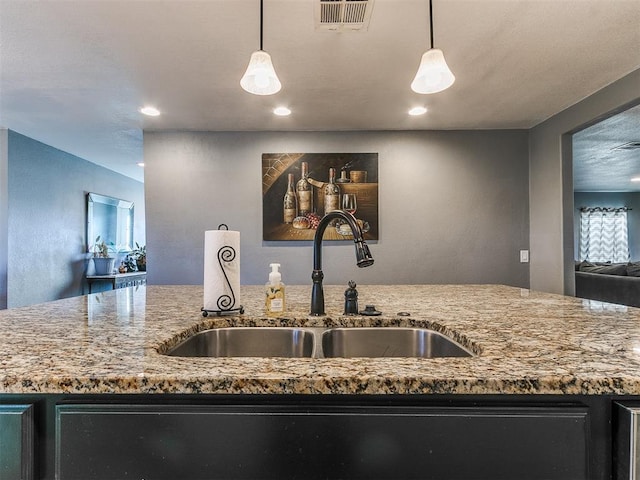 kitchen with pendant lighting, light stone countertops, and sink