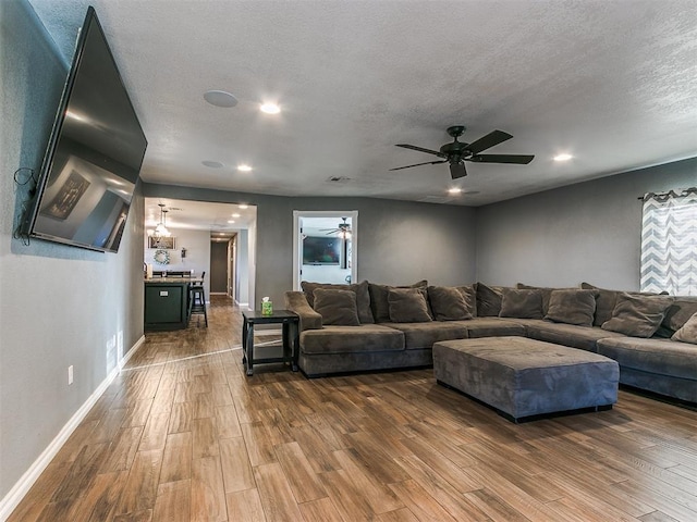 living room with wood-type flooring, ceiling fan, and a textured ceiling