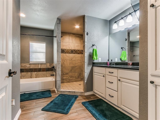 bathroom featuring vanity, shower with separate bathtub, hardwood / wood-style floors, and a textured ceiling