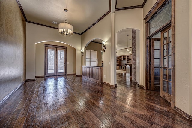 foyer entrance with dark hardwood / wood-style flooring, crown molding, french doors, and a chandelier