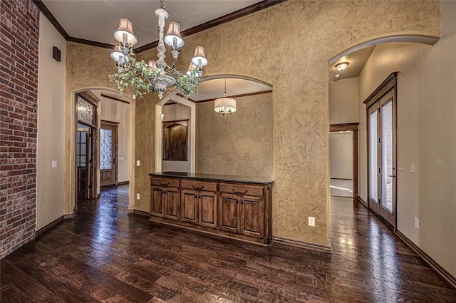 unfurnished dining area featuring ornamental molding, brick wall, a chandelier, and dark hardwood / wood-style flooring