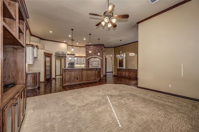 kitchen with crown molding, hanging light fixtures, a center island with sink, stainless steel microwave, and ceiling fan with notable chandelier