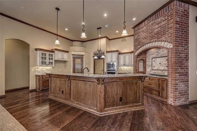 kitchen featuring a breakfast bar area, backsplash, hanging light fixtures, a large island, and dark wood-type flooring