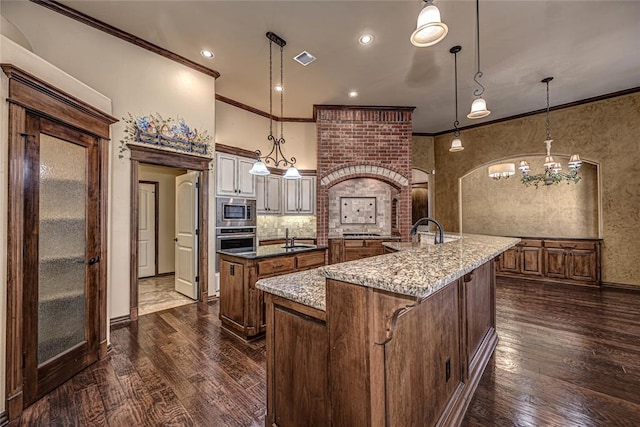 kitchen featuring hanging light fixtures, stainless steel appliances, sink, and a center island with sink