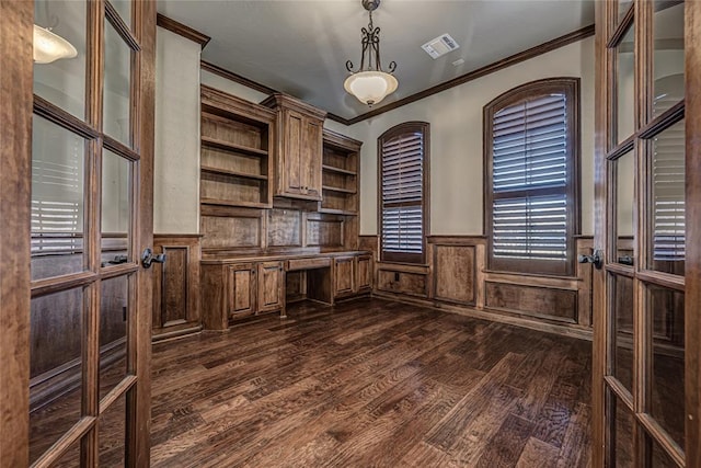 unfurnished office with built in desk, dark wood-type flooring, and ornamental molding