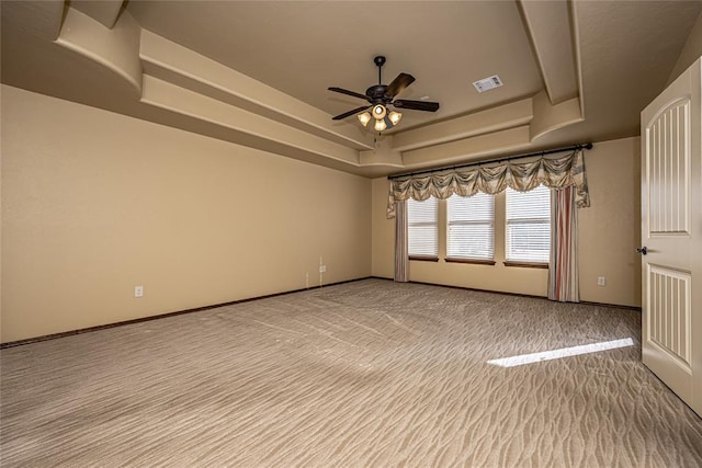 spare room featuring carpet flooring, ceiling fan, and a tray ceiling