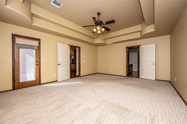 carpeted empty room featuring a raised ceiling and ceiling fan