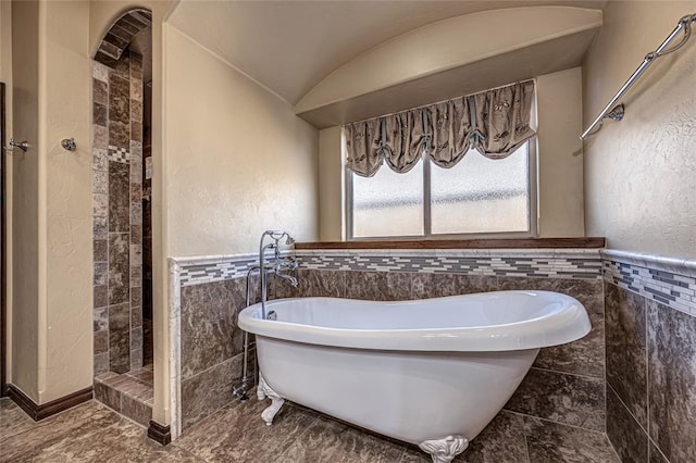 bathroom featuring separate shower and tub, tile walls, and lofted ceiling