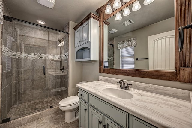 bathroom with a shower with door, vanity, tile patterned floors, and toilet