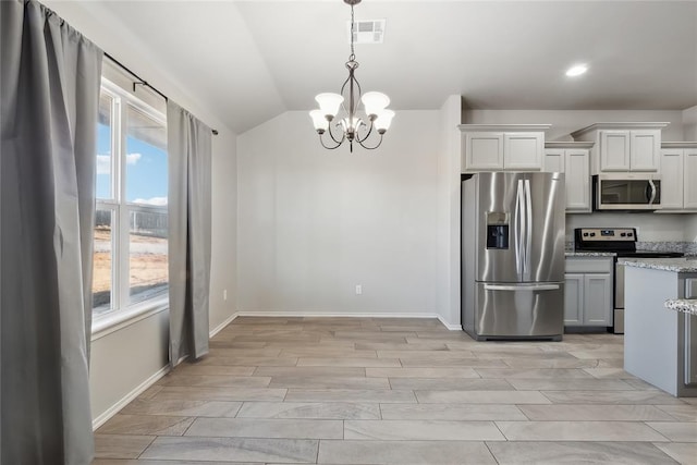 kitchen with appliances with stainless steel finishes, pendant lighting, white cabinetry, lofted ceiling, and light stone counters