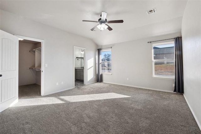 unfurnished bedroom featuring light carpet, a spacious closet, lofted ceiling, and ceiling fan