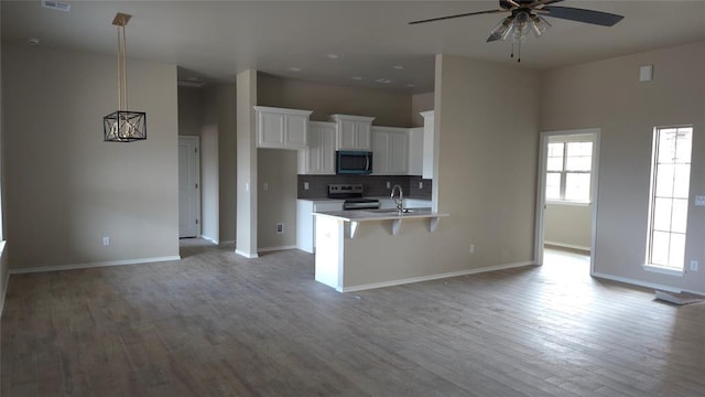 kitchen featuring a kitchen bar, light hardwood / wood-style flooring, white cabinetry, stainless steel appliances, and decorative backsplash