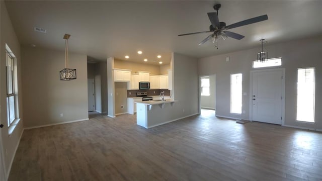 unfurnished living room featuring ceiling fan, sink, and wood-type flooring