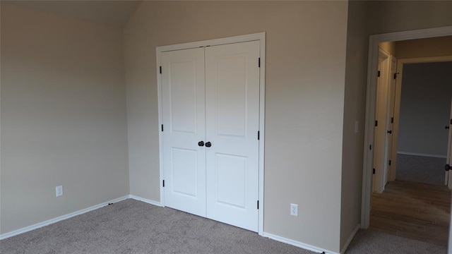 unfurnished bedroom with a closet, lofted ceiling, and light colored carpet