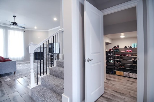 stairway with hardwood / wood-style floors, crown molding, and ceiling fan