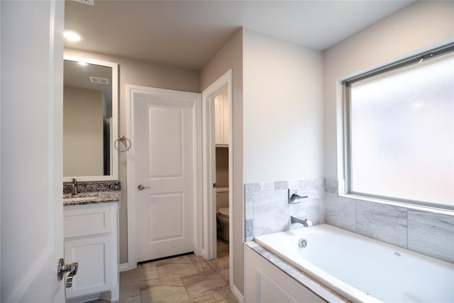 bathroom featuring vanity, toilet, and a washtub