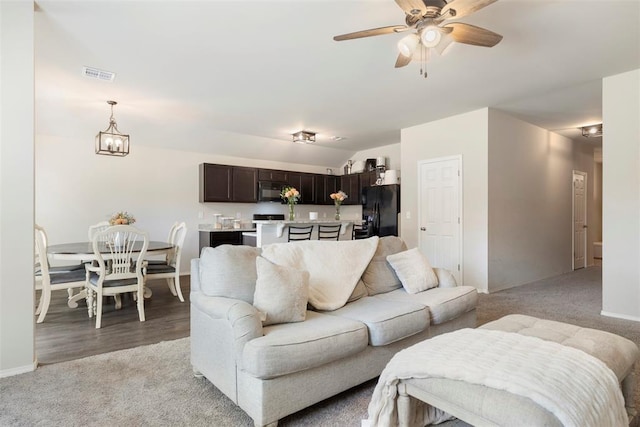 carpeted living room featuring lofted ceiling and ceiling fan with notable chandelier