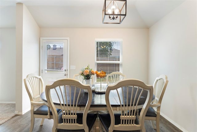 dining space with a notable chandelier, hardwood / wood-style flooring, and vaulted ceiling