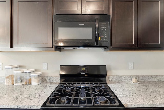 kitchen featuring light stone counters, dark brown cabinets, and black appliances