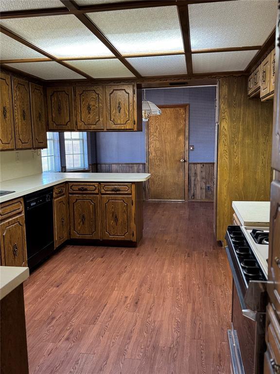 kitchen featuring dark hardwood / wood-style floors, dishwasher, coffered ceiling, range, and kitchen peninsula