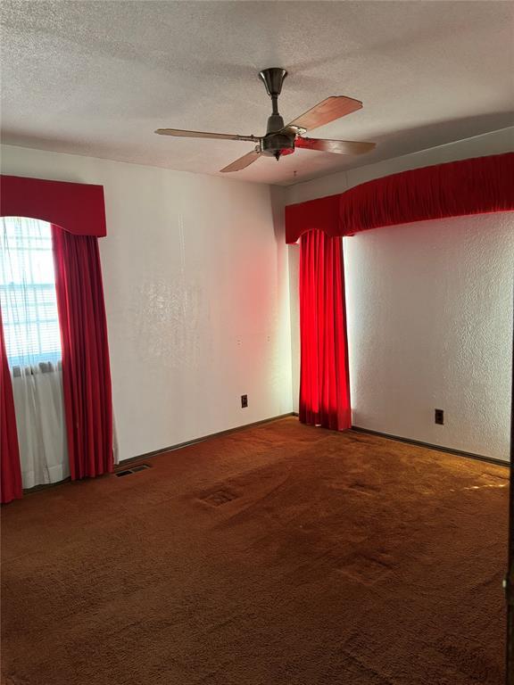 empty room featuring ceiling fan, carpet floors, and a textured ceiling