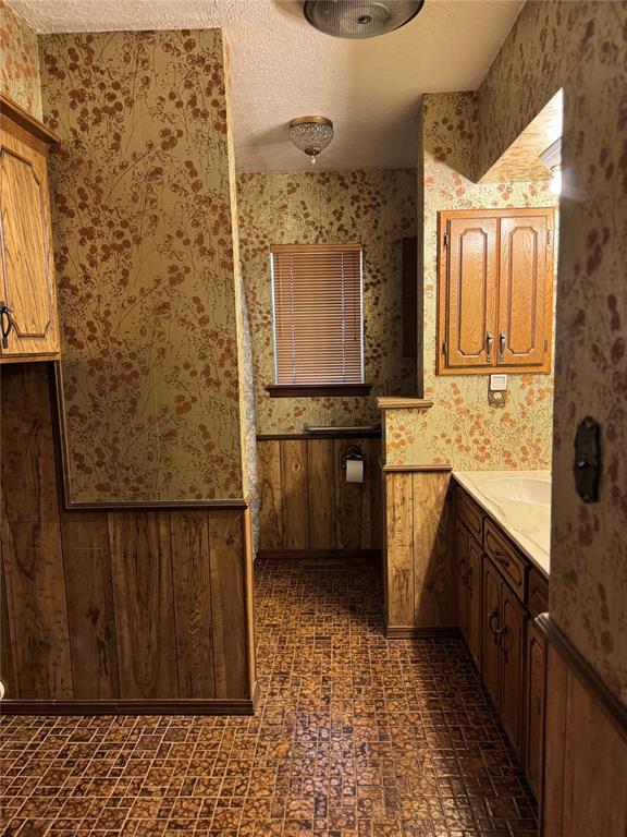 bathroom featuring vanity, wooden walls, and a textured ceiling