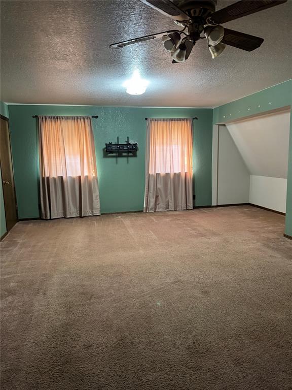 carpeted empty room with ceiling fan and a textured ceiling