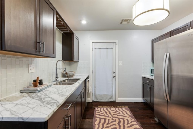 kitchen with appliances with stainless steel finishes, light stone countertops, sink, and dark brown cabinets