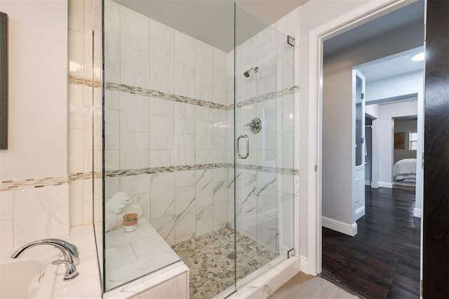 bathroom featuring wood-type flooring and separate shower and tub