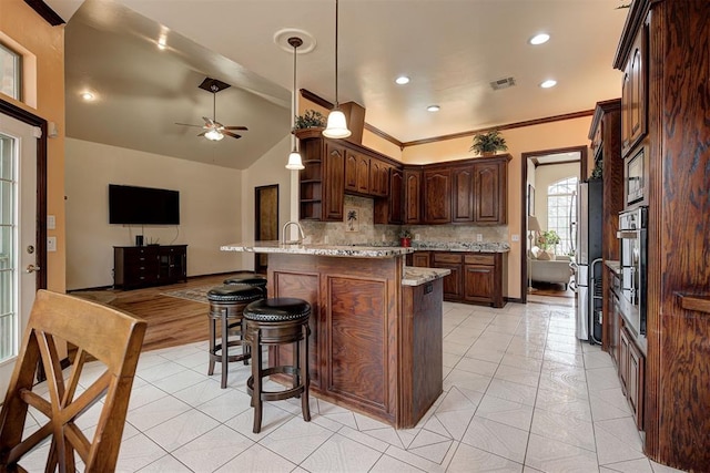 kitchen with lofted ceiling, stainless steel appliances, tasteful backsplash, light stone countertops, and light tile patterned flooring