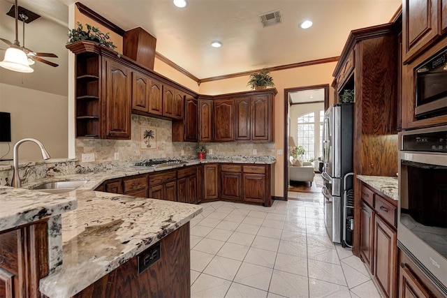 kitchen with light stone counters, stainless steel appliances, sink, and backsplash