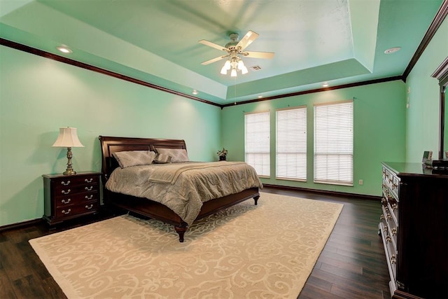 bedroom with dark hardwood / wood-style floors, ceiling fan, a tray ceiling, and crown molding