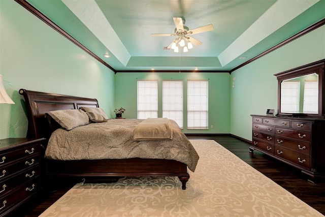 bedroom with crown molding, dark hardwood / wood-style floors, ceiling fan, and a tray ceiling