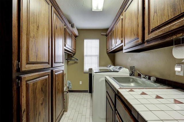 laundry room featuring cabinets, separate washer and dryer, and sink