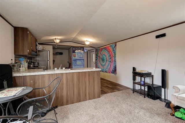 kitchen featuring vaulted ceiling, sink, stainless steel fridge, dark carpet, and kitchen peninsula