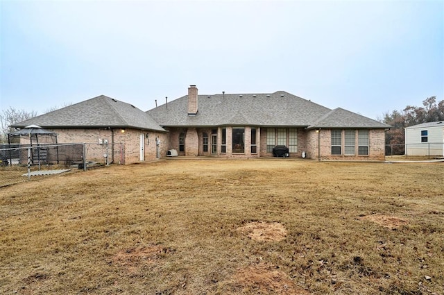 rear view of house with a gazebo and a lawn