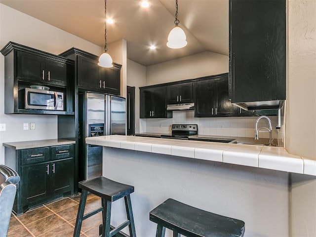 kitchen with appliances with stainless steel finishes, decorative light fixtures, sink, and tile countertops