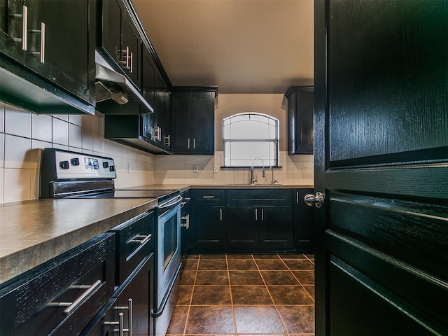 kitchen with sink, electric range, dark tile patterned floors, and backsplash