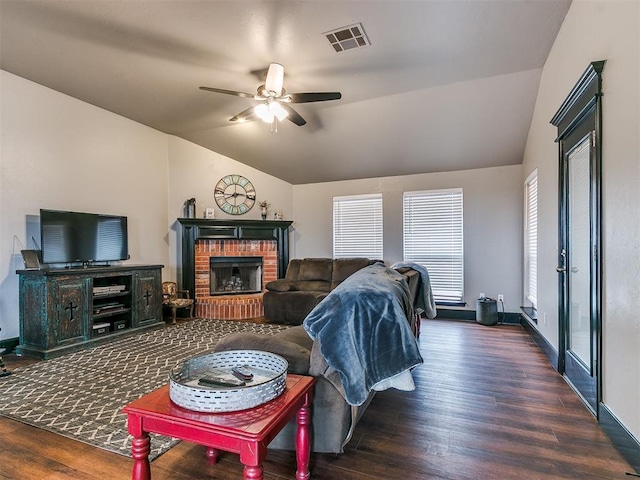 living room with dark wood-type flooring, ceiling fan, vaulted ceiling, and a brick fireplace