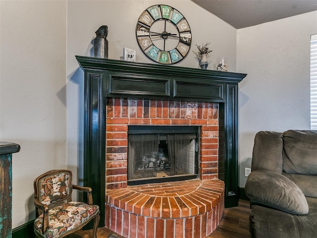 living area featuring a brick fireplace and dark hardwood / wood-style floors