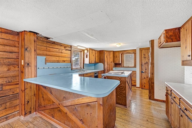 kitchen featuring a kitchen breakfast bar, kitchen peninsula, a textured ceiling, and light wood-type flooring