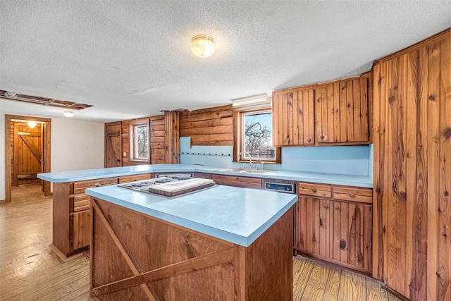 kitchen featuring sink, a textured ceiling, light wood-type flooring, kitchen peninsula, and a kitchen island