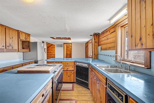 kitchen with appliances with stainless steel finishes, sink, a textured ceiling, and light wood-type flooring