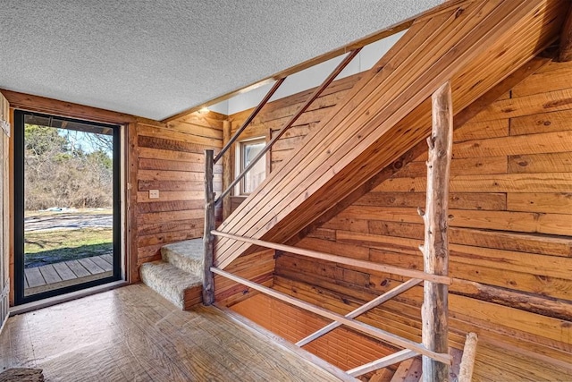 interior space with a textured ceiling and wood walls