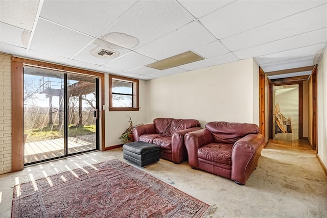 carpeted living room featuring a drop ceiling