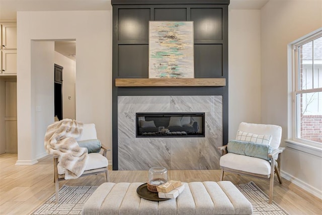 living room with a high end fireplace and light hardwood / wood-style flooring