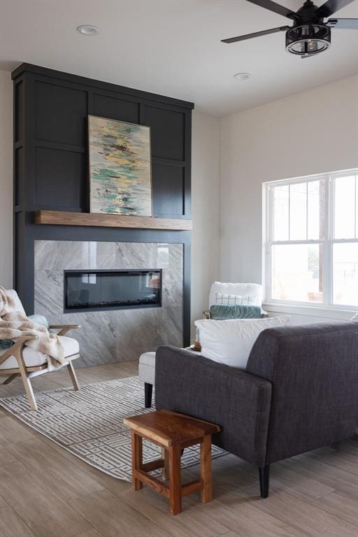 living room featuring ceiling fan, a fireplace, and light hardwood / wood-style flooring