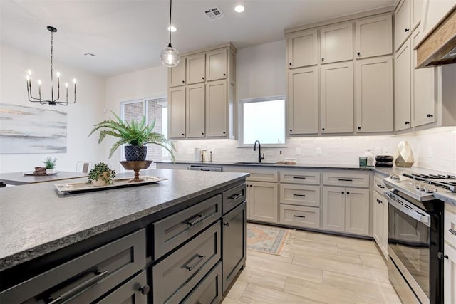 kitchen with sink, gray cabinetry, hanging light fixtures, stainless steel gas range oven, and custom range hood