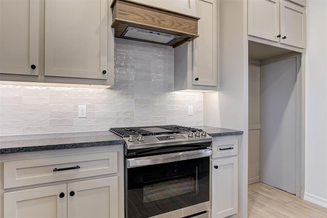 kitchen featuring premium range hood, white cabinetry, tasteful backsplash, light hardwood / wood-style flooring, and stainless steel range with gas cooktop