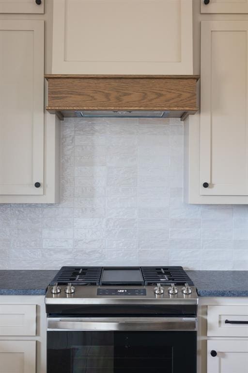 kitchen with backsplash, gas stove, and white cabinets